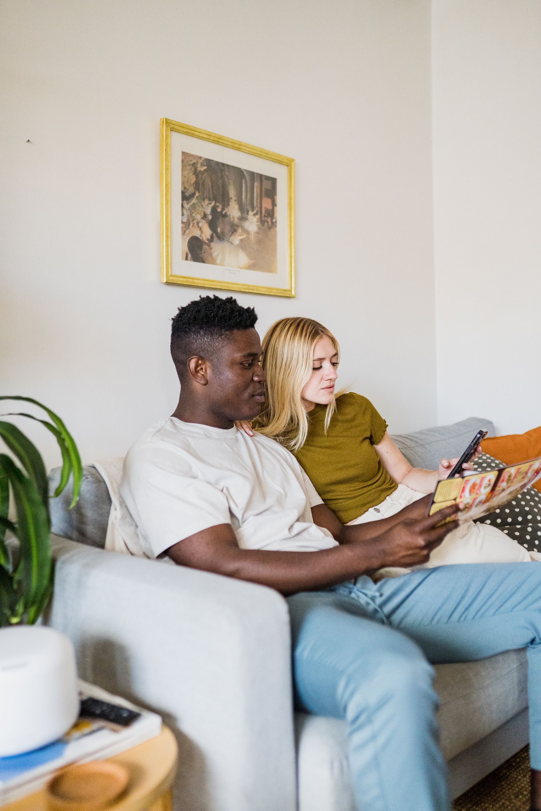 A couple reading together on a sofa at home