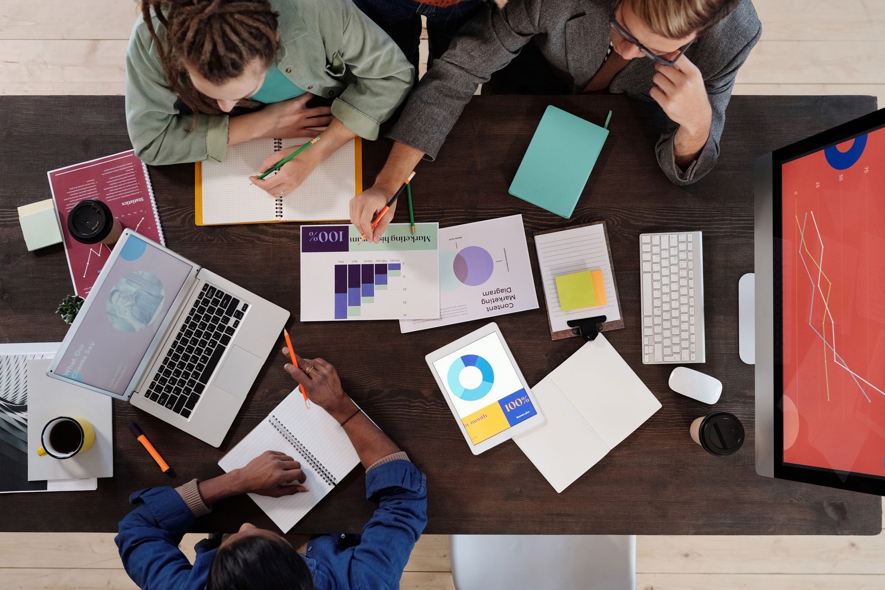 Overhead view of a desk covered in paperwork as a team works through a file
